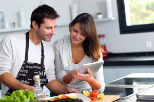 Man and woman preparing dinner using tablet